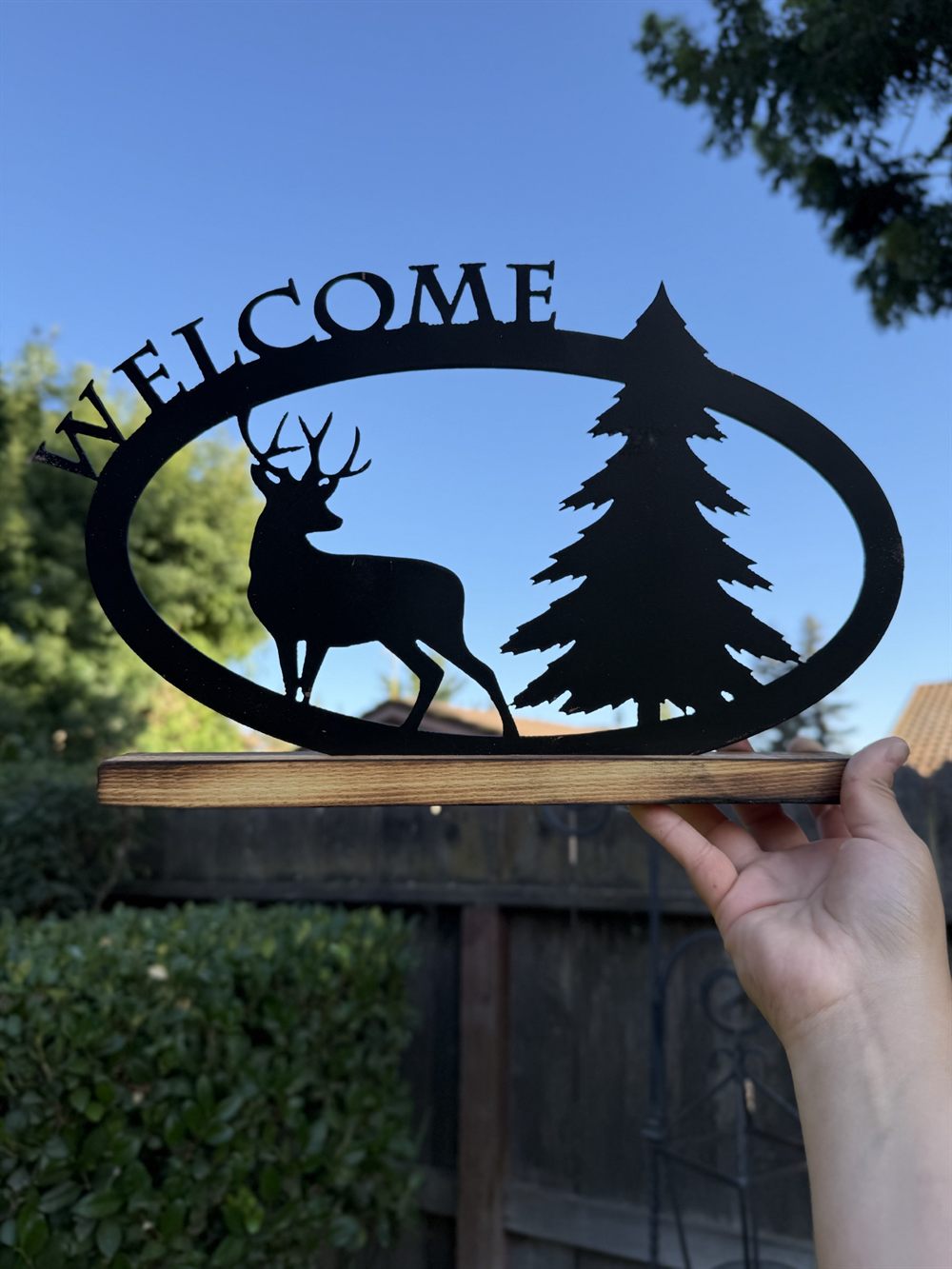 A steel Welcome sign with a buck and pine tree in an oval.